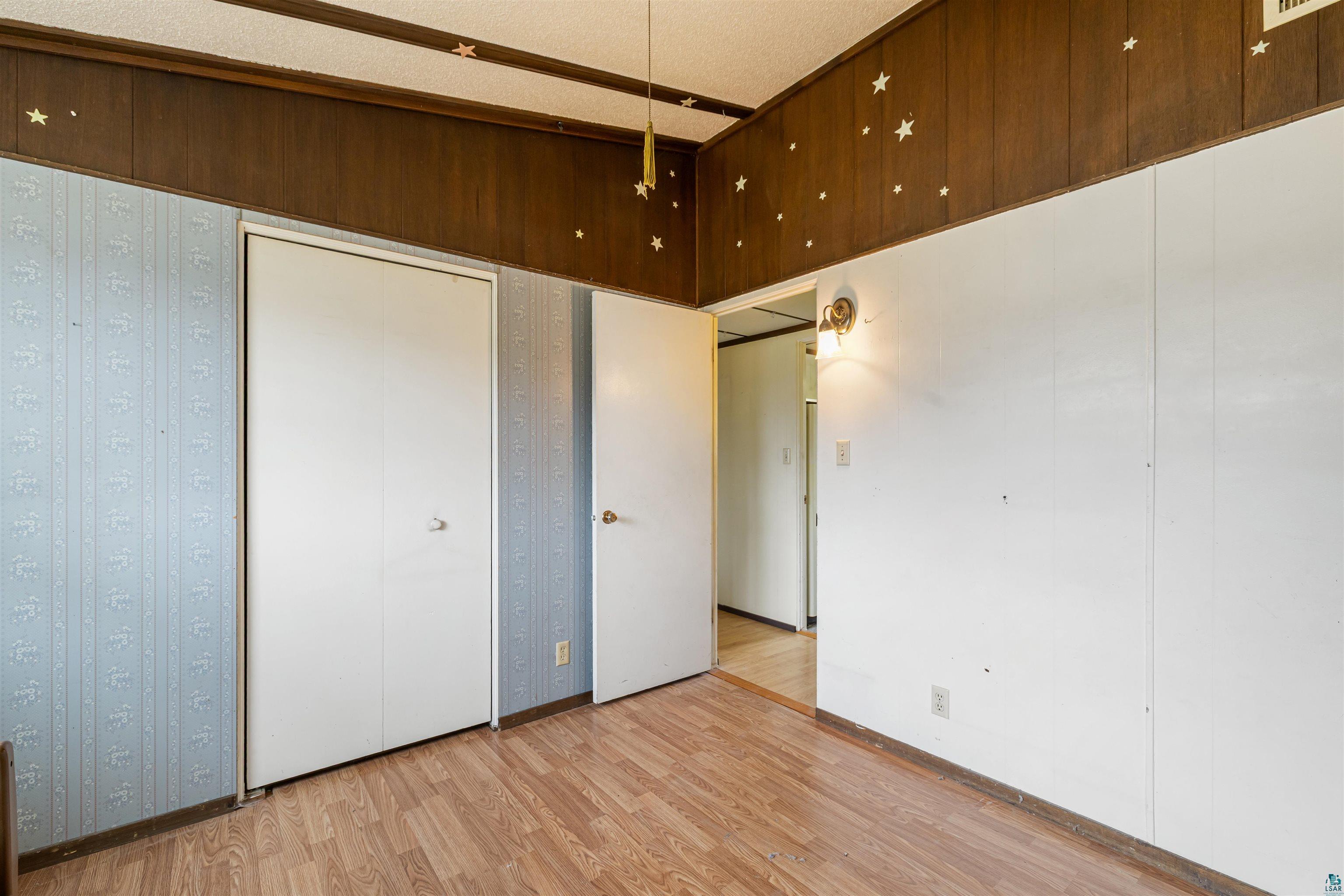 11574 Town Line Road Hibbing, MN 55746 - Photo 17 of 41 Room featuring wood-finish flooring, two white bi-fold closet doors, and white paneled walls