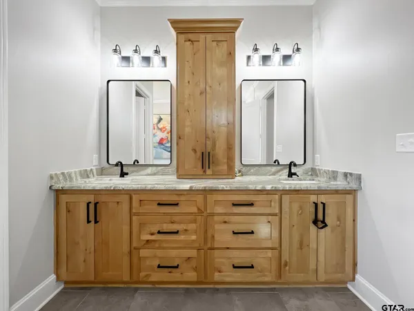 a bathroom with a granite countertop double vanity sink and a mirror