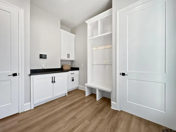 a kitchen with white cabinets and wooden floor