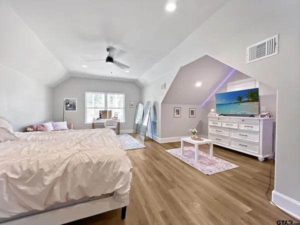 a spacious bedroom with a bed and a flat screen tv