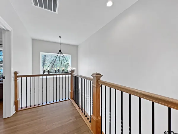 a view of a hallway with wooden floor and a chandelier
