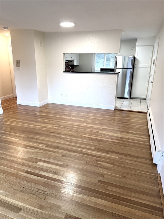 25 Lionel Avenue, Unit E Waltham, MA 02452 - Photo 10 of 13 a view of kitchen and empty room with wooden floor