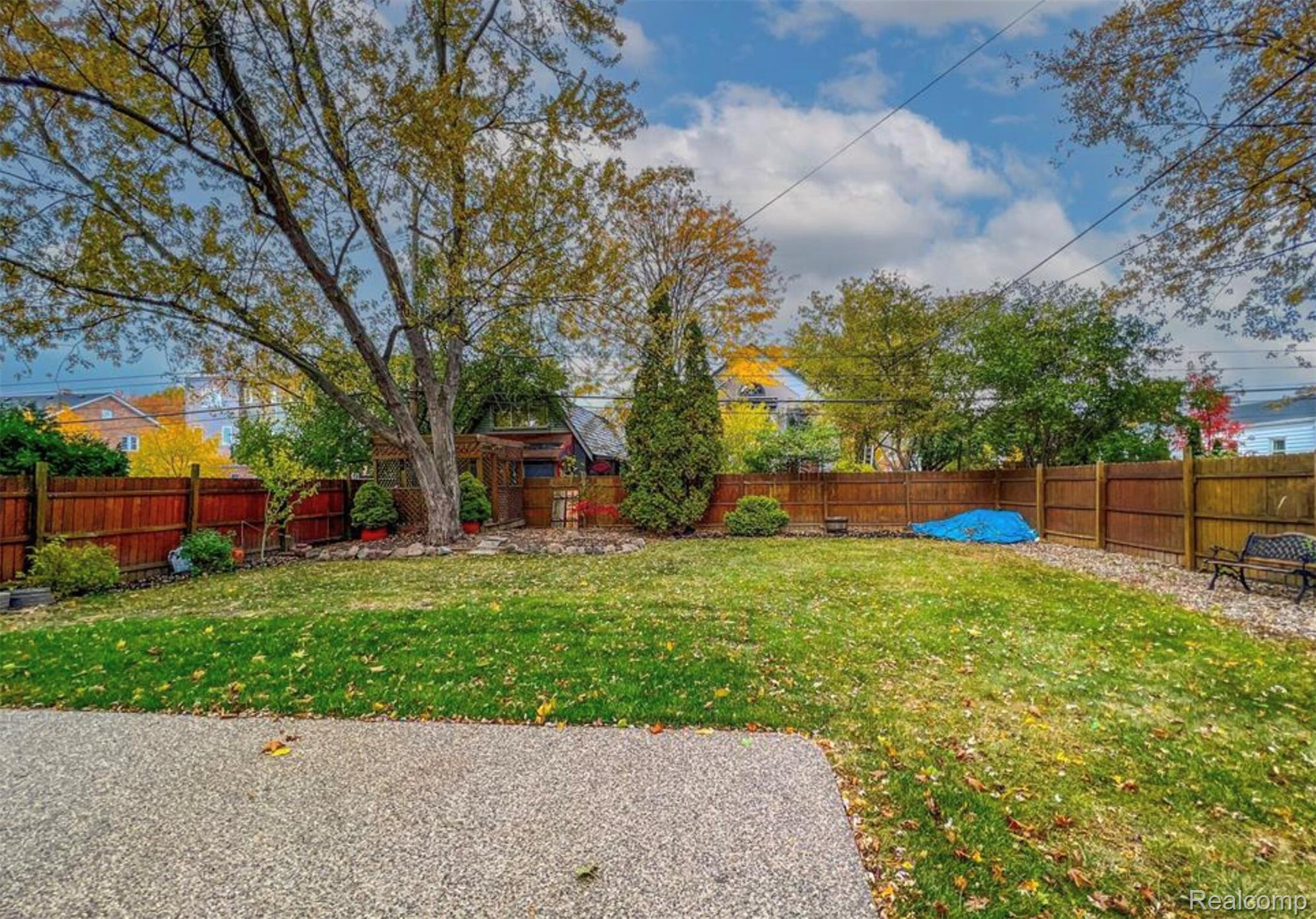 4214 Berkshire Road Royal Oak, MI 48073 - Photo 26 of 27 Expansive backyard featuring a large green lawn, concrete patio, full privacy fencing, established trees, and a wooden shed structure