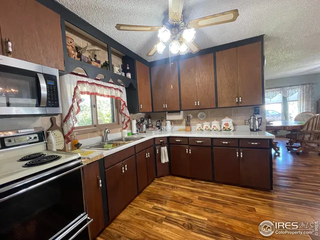 a kitchen with stainless steel appliances granite countertop a sink cabinets and wooden floor