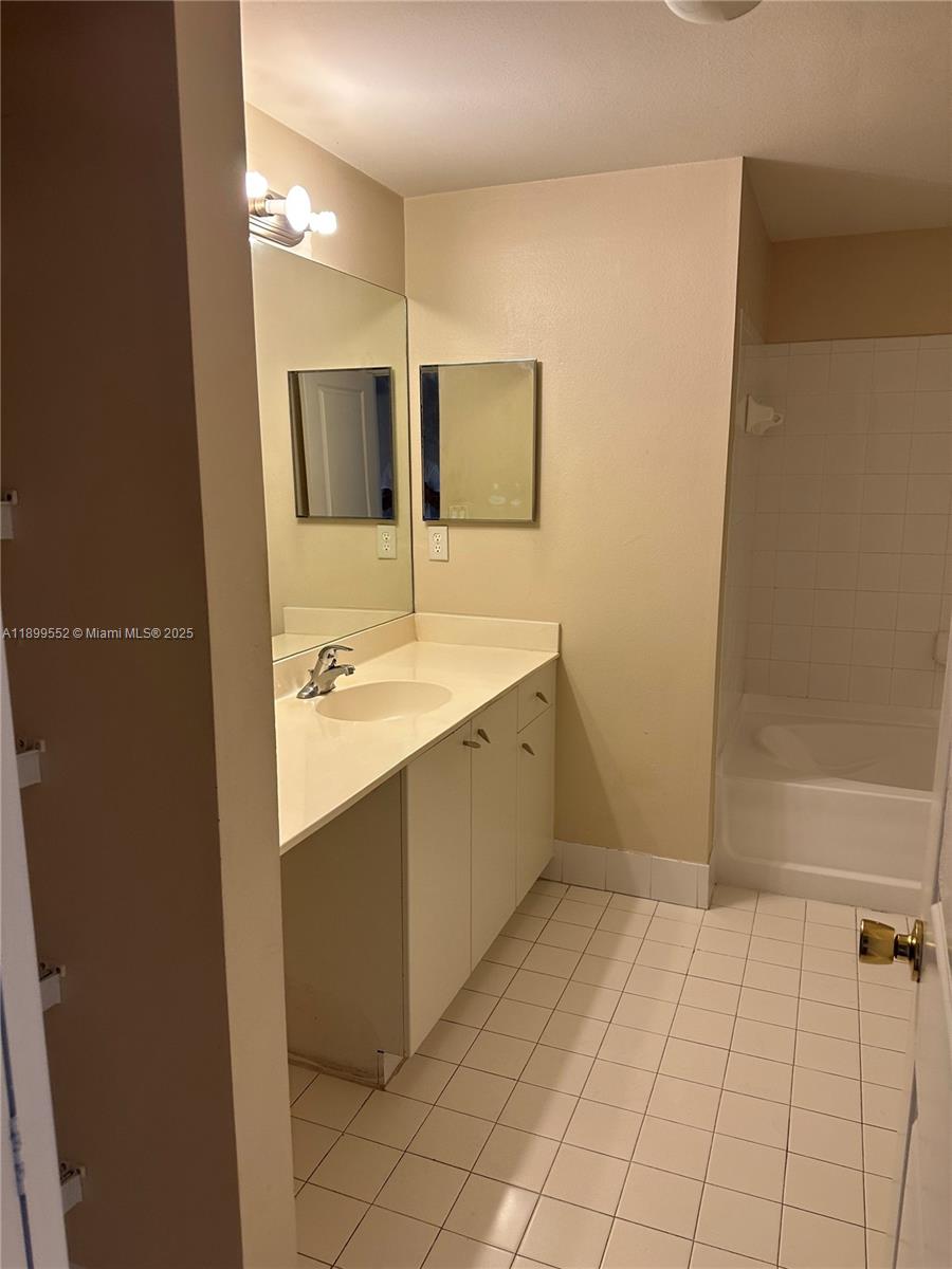 5840 West Sample Road, Unit 306 Coral Springs, FL 33067 - Photo 16 of 22 a bathroom with a sink a mirror and a bathtub
