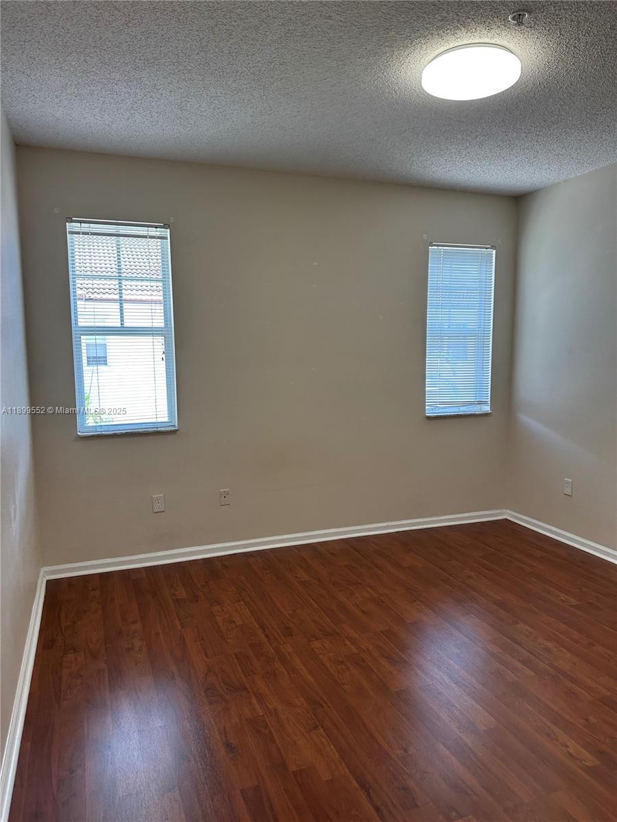 5840 West Sample Road, Unit 306 Coral Springs, FL 33067 - Photo 18 of 22 an empty room with wooden floor and windows