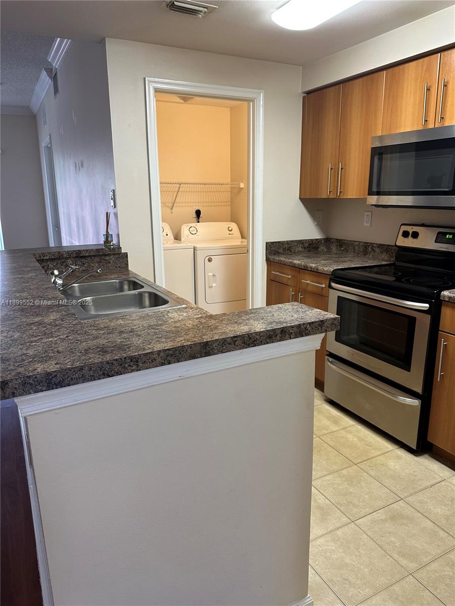 5840 West Sample Road, Unit 306 Coral Springs, FL 33067 - Photo 3 of 22 a kitchen with kitchen island granite countertop a sink cabinets and stainless steel appliances