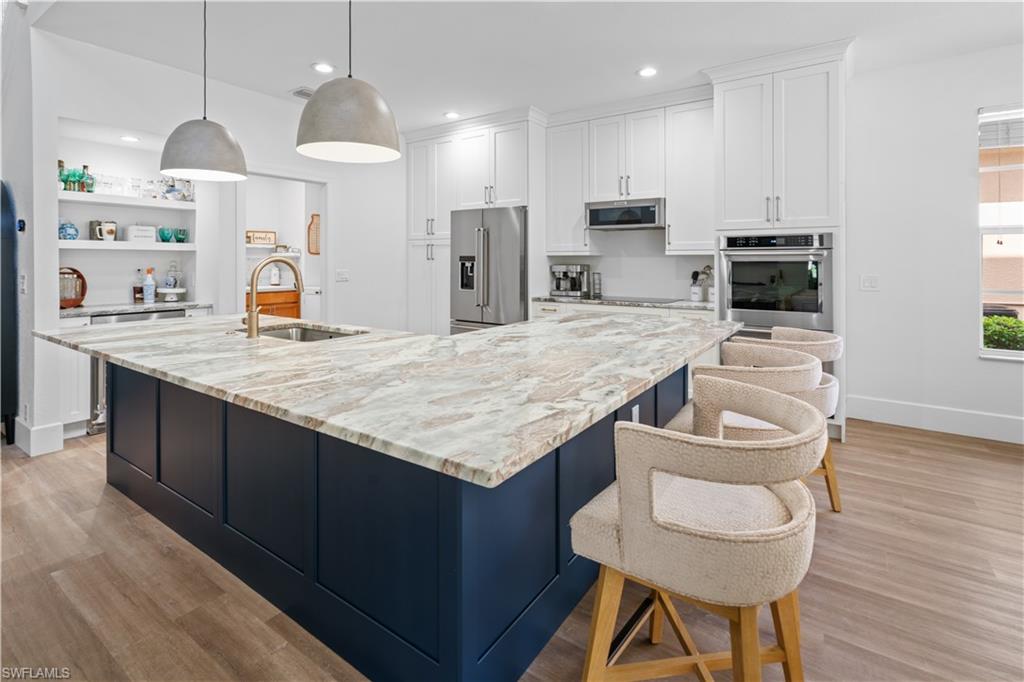 a kitchen with granite countertop kitchen island stainless steel appliances a sink and a refrigerator