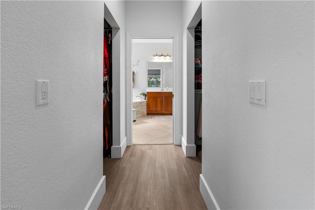 15917 Delasol Lane Naples, FL 34110 - Photo 16 of 32 a view of a hallway with wooden floor and a bathroom