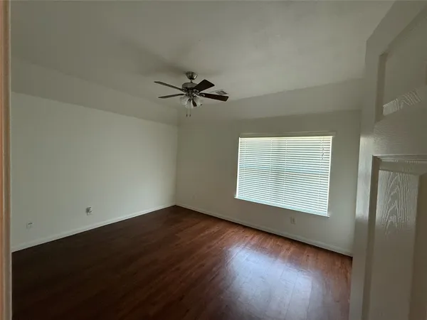 an empty room with wooden floor fan and windows