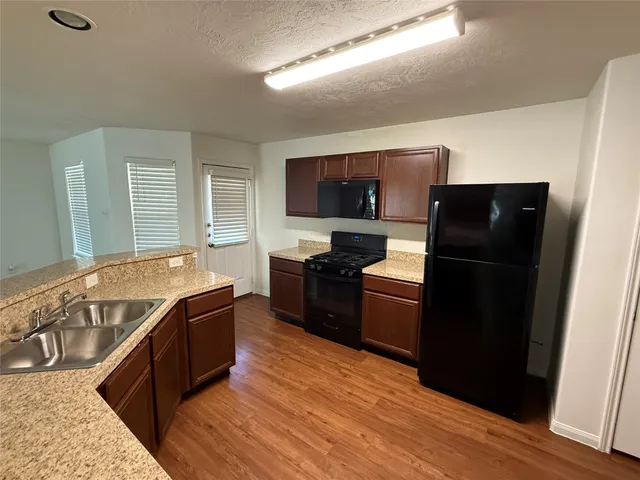 a living room with stainless steel appliances granite countertop a refrigerator stove and sink