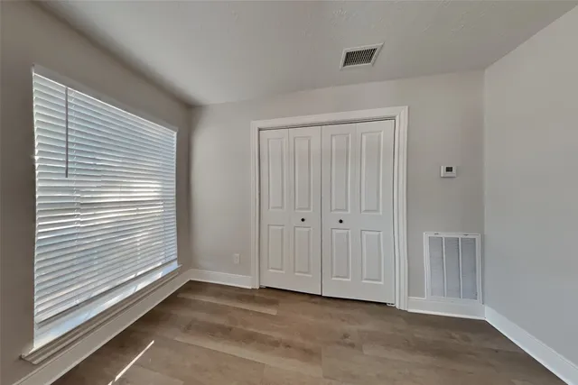 a view of an empty room with window and closet area