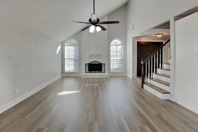 a view of a livingroom with wooden floor a ceiling fan and windows
