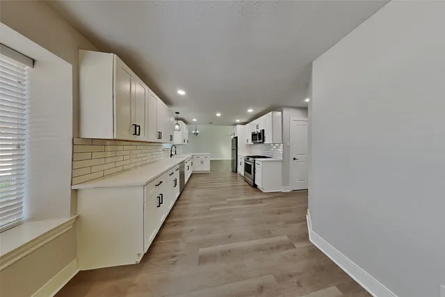 a large white kitchen with a white stove top oven and kitchen island