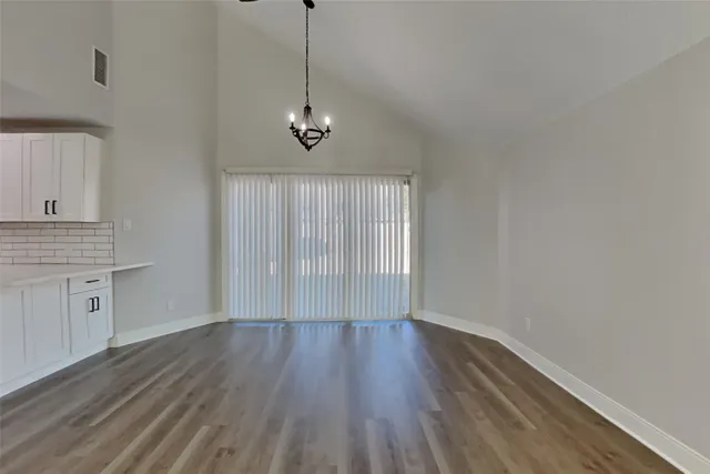 a view of a room with wooden floor a kitchen space and a window