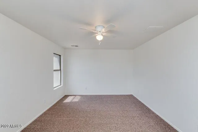 a view of an empty room with chandelier fan