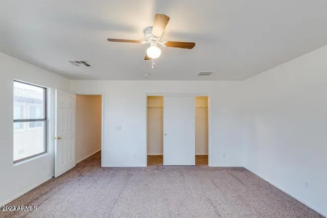 an empty room with windows and ceiling fan