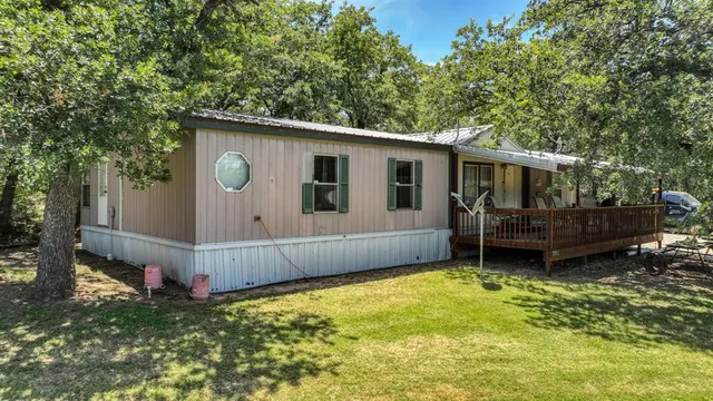 a backyard of a house with wooden fence and a tree