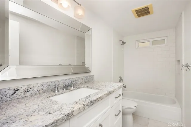 a bathroom with a granite countertop sink toilet and shower
