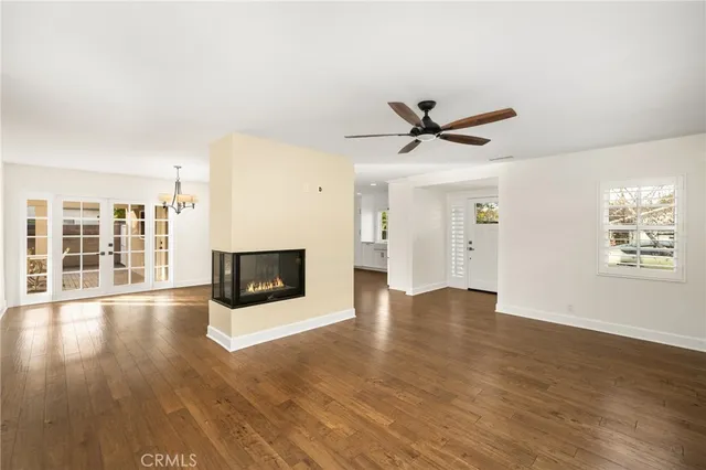 an empty room with wooden floor a ceiling fan and windows