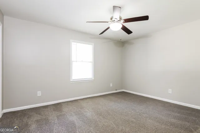 an empty room with a ceiling fan and windows