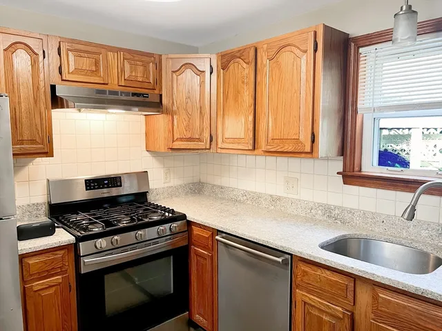 a kitchen with granite countertop a sink stainless steel appliances cabinets and a window