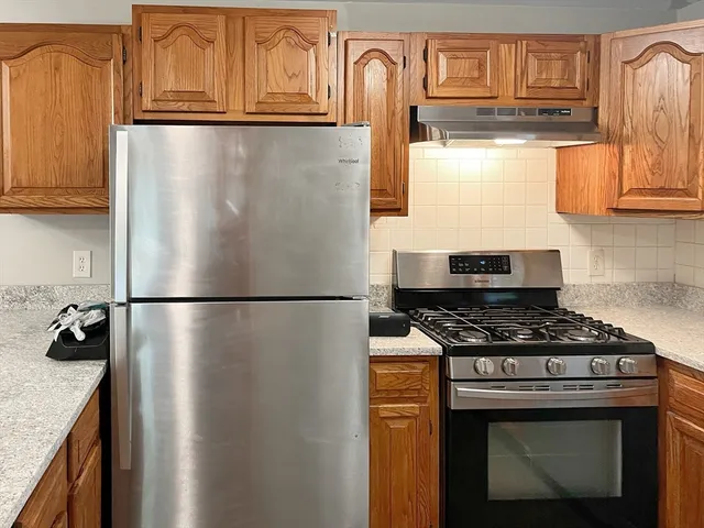 a kitchen with stainless steel appliances granite countertop a refrigerator a stove and a sink