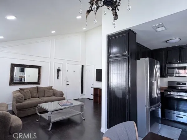 a living room with stainless steel appliances furniture and a view of kitchen