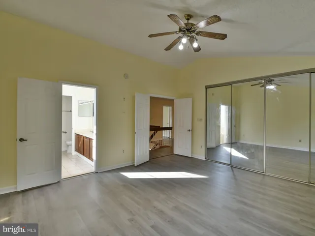a view of an empty room with wooden floor and closet