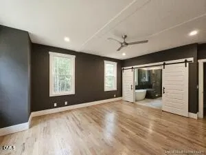 an empty room with wooden floor fan and windows