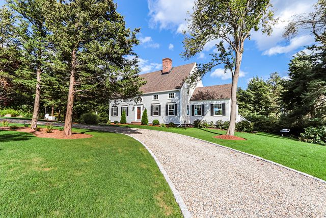 a view of a house with a big yard plants and large trees