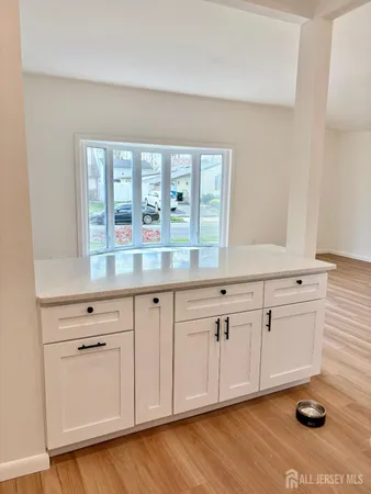 a kitchen with granite countertop white cabinets and white appliances with wooden floor