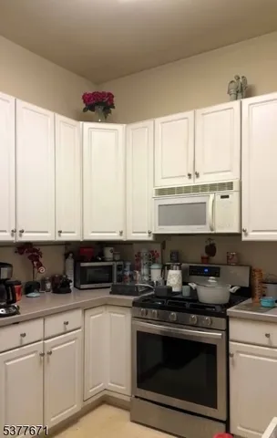 a kitchen with stainless steel appliances granite countertop a stove a sink and white cabinets
