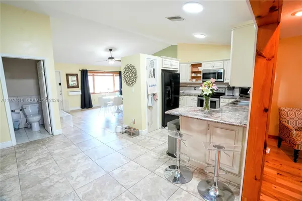 a kitchen with stainless steel appliances kitchen island granite countertop a refrigerator and cabinets
