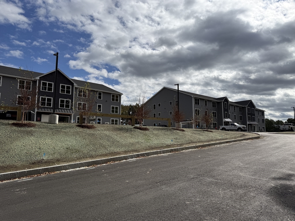 251 Sladen Street, Unit 103 Dracut, MA 01826 - Photo 20 of 27 a view of a house with wooden fence next to a house