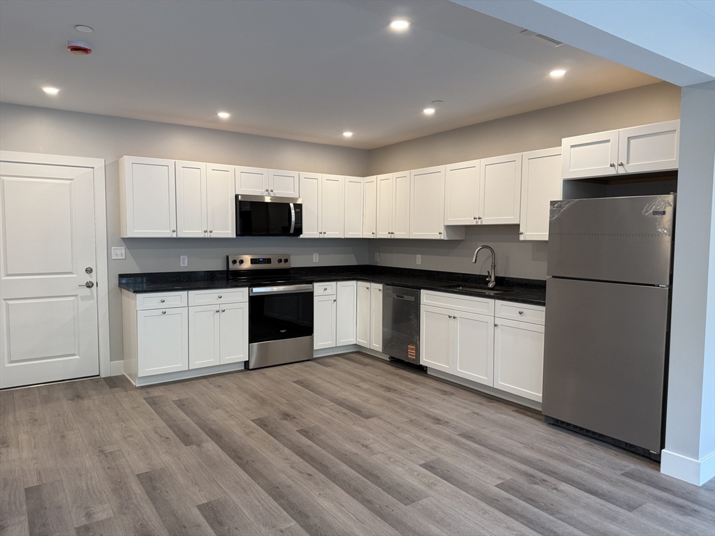 251 Sladen Street, Unit 103 Dracut, MA 01826 - Photo 2 of 27 a kitchen with granite countertop a refrigerator sink and white cabinets