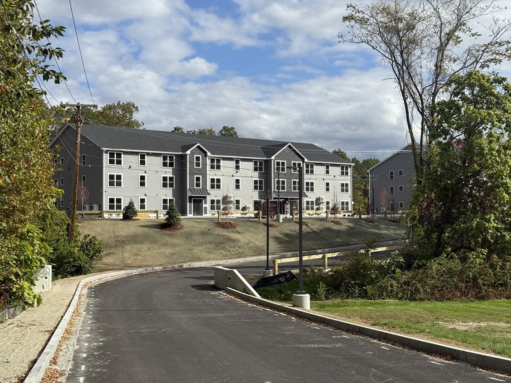 251 Sladen Street, Unit 103 Dracut, MA 01826 - Photo 27 of 27 a view of a town with brick house and large tree and plants