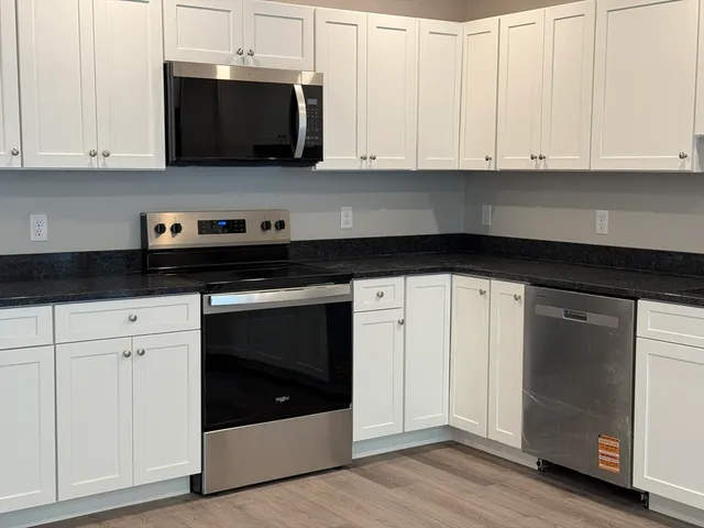 a kitchen with stainless steel appliances granite countertop white cabinets and a granite counter tops