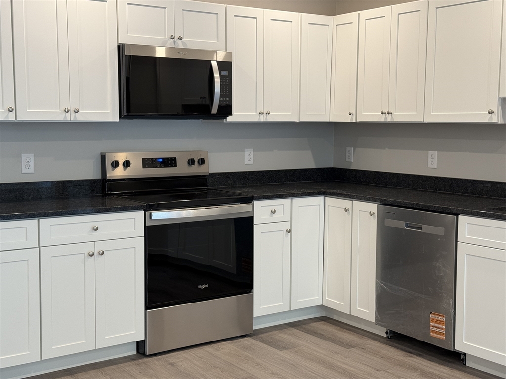 251 Sladen Street, Unit 103 Dracut, MA 01826 - Photo 3 of 27 a kitchen with stainless steel appliances granite countertop white cabinets and a granite counter tops