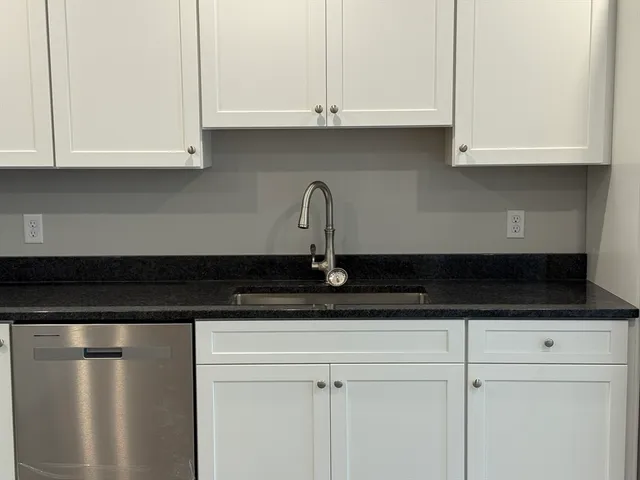 a kitchen with granite countertop white cabinets and a sink