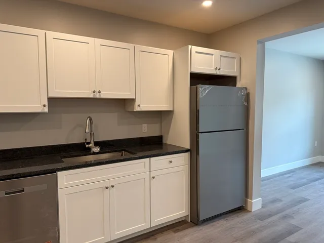 a kitchen with granite countertop white cabinets and a refrigerator