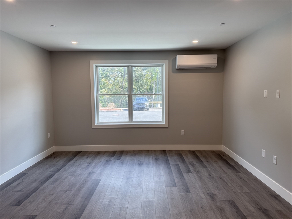 251 Sladen Street, Unit 103 Dracut, MA 01826 - Photo 6 of 27 an empty room with wooden floor and windows