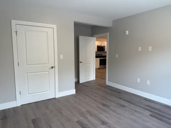 a view of an empty room with wooden floor and closet