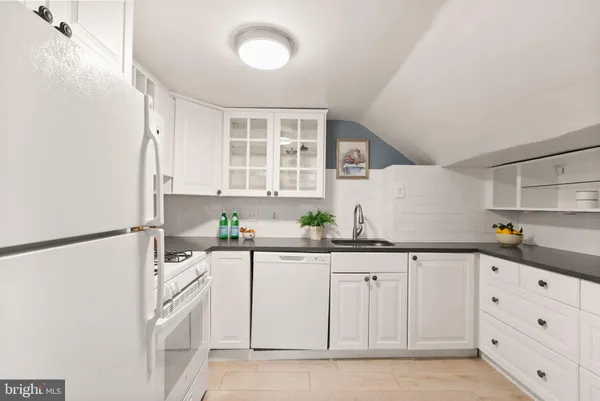 a kitchen with white cabinets and sink