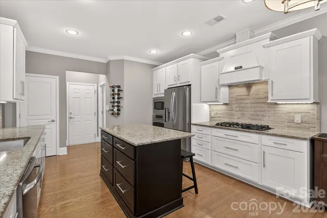 a kitchen with granite countertop a stove a sink a dining table and chairs