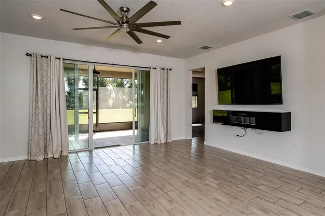 a view of a livingroom with a flat screen tv wooden floor and a ceiling fan