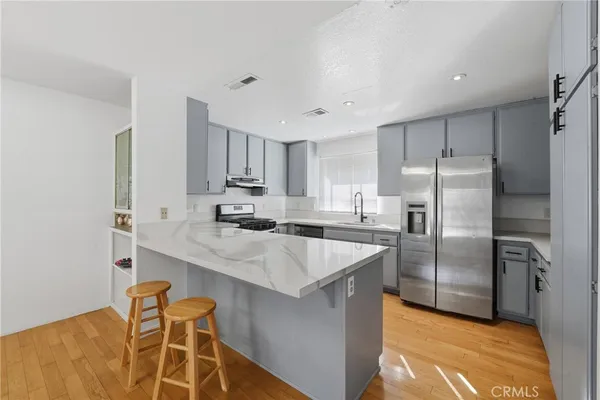 a kitchen with kitchen island granite countertop a sink refrigerator and cabinets