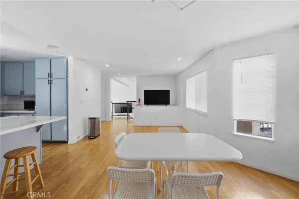 a living room with stainless steel appliances furniture a flat screen tv and a wooden floor