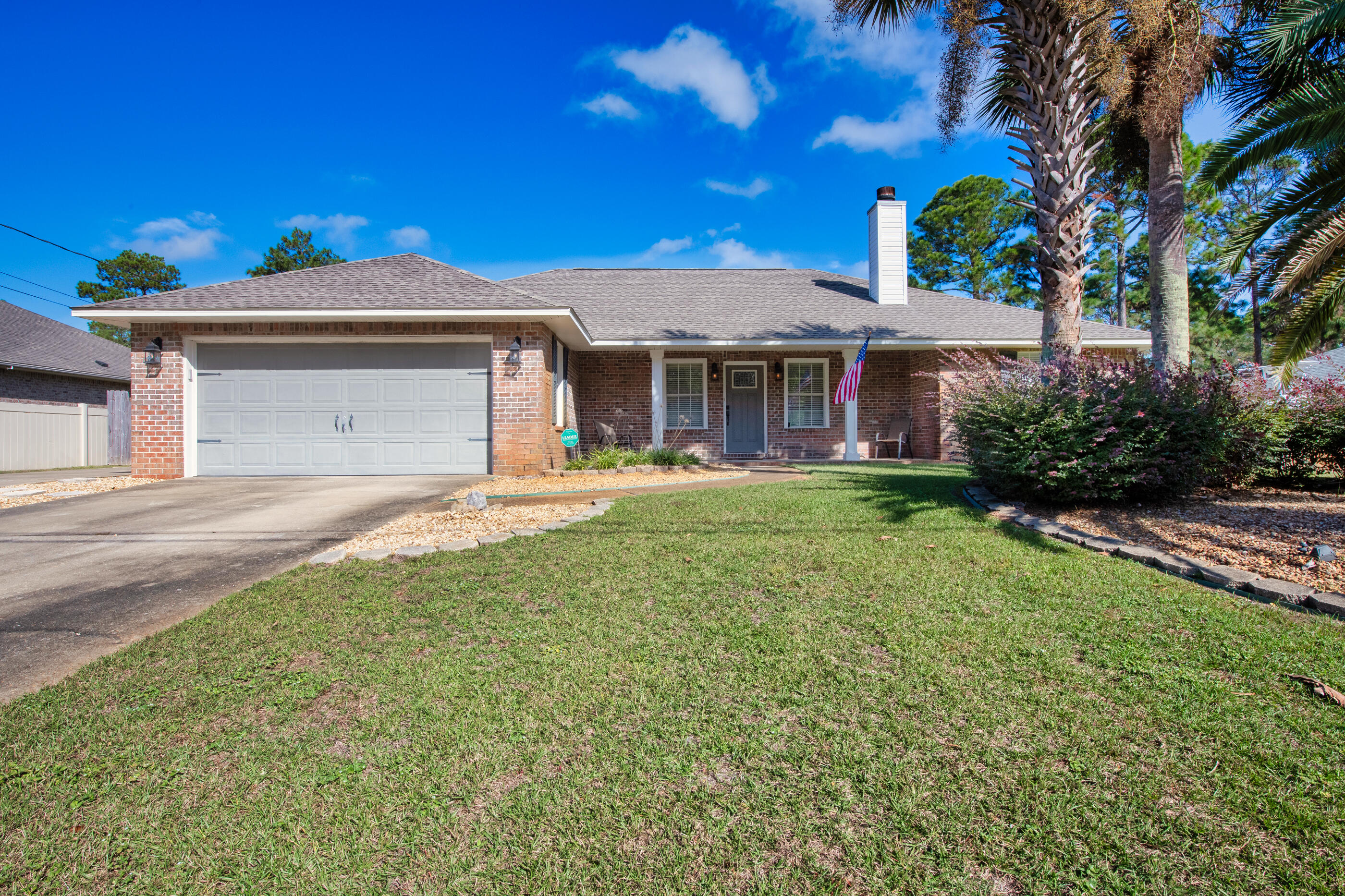 6664 Bellingham Street Navarre, FL 32566 - Photo 2 of 28 a front view of a house with a yard and palm trees