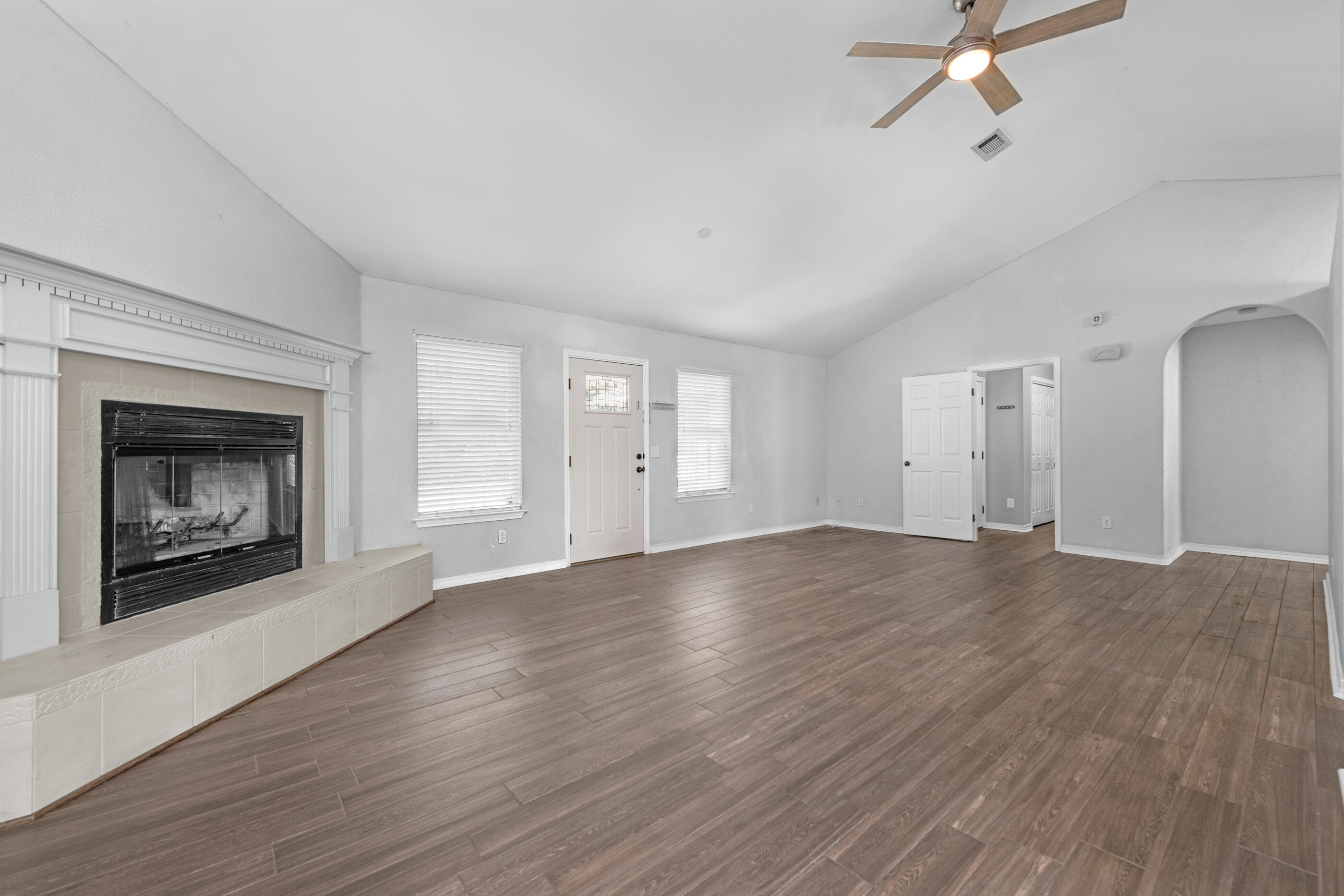 6664 Bellingham Street Navarre, FL 32566 - Photo 3 of 28 an empty room with wooden floor fireplace and windows